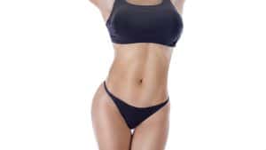 A woman in a black swimsuit before a nipple reduction procedure